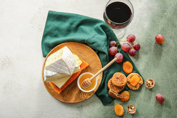 Glass of wine, different types of cheese and snacks on color background - Photo, Image