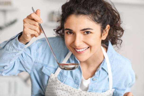 Młoda kobieta degustacja danie w kuchni - Zdjęcie, obraz