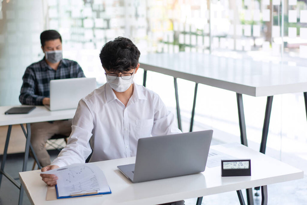 Concepto Covid-19 dos hombres de negocios que llevan una máscara de planificación para el nuevo proyecto de mantenimiento de distanciamiento social en el lugar de trabajo durante el brote de Coronavirus (COVID-19). - Foto, imagen