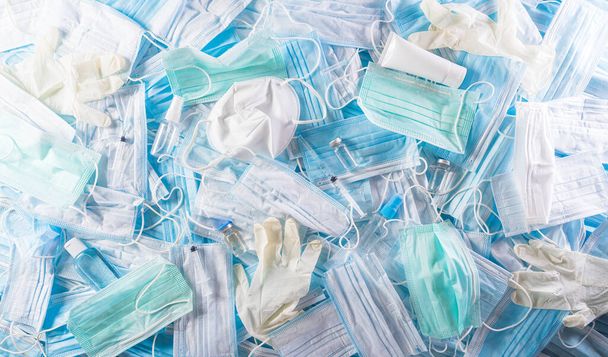 Ansicht von Covid-19 Plastikmüll und -müll, Einmalmasken, Medikamentenhandschuh, Alkoholgelflasche und -nadel. Verschmutzung durch Chirurgenmasken während der Coronavirus-Pandemie. - Foto, Bild