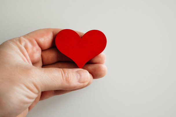 wooden red heart in hand, on a white background. - Foto, Imagen