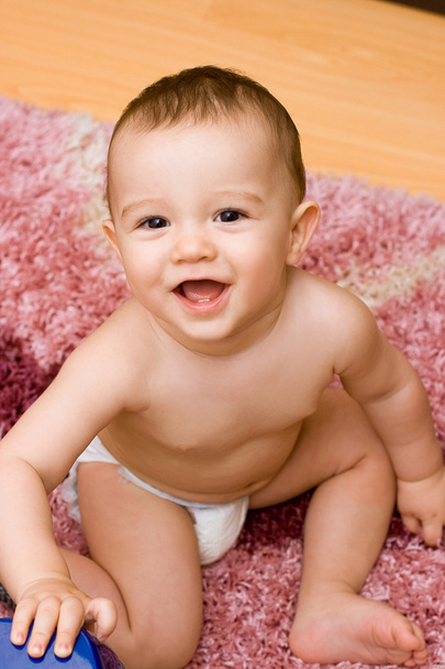 Smiling caucasain baby sitting on the carpet - Foto, afbeelding
