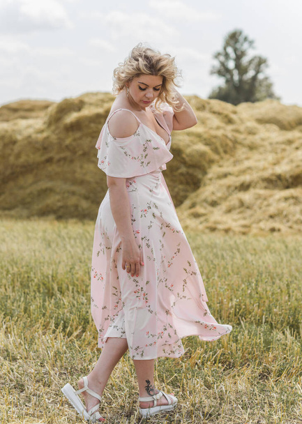 Сельский винтажный стиль смеси, плюс размер женщины в мягком хлопчатобумажном светлом платье на поле. Портрет милой дамы на сеновале - Фото, изображение