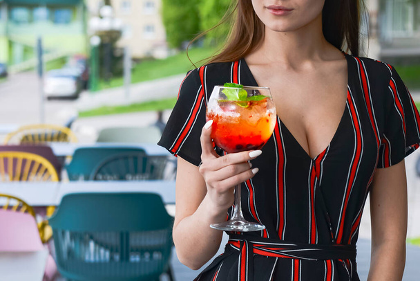 Young woman with aperol spritz soda cocktail in outdoor restaurant. Eat out concept, eating alone due to worldwide pandemic. Copy space banner. - 写真・画像