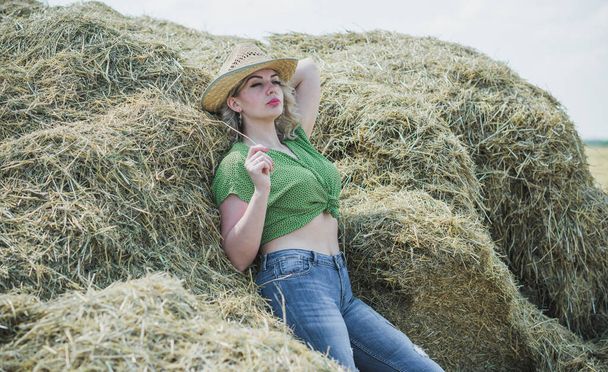 Plus size model in American country style at the hay. Concept of fashionable style and vogue - Photo, Image