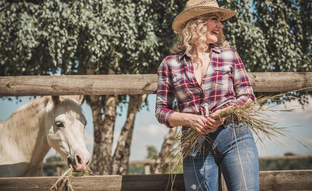 Amerikanischer Landhausstil, Frau im Gespräch mit ihrem Pferd. Porträt eines Reiters mit Frau im karierten Hemd, Pferd mit Frau auf der Rancho - Foto, Bild