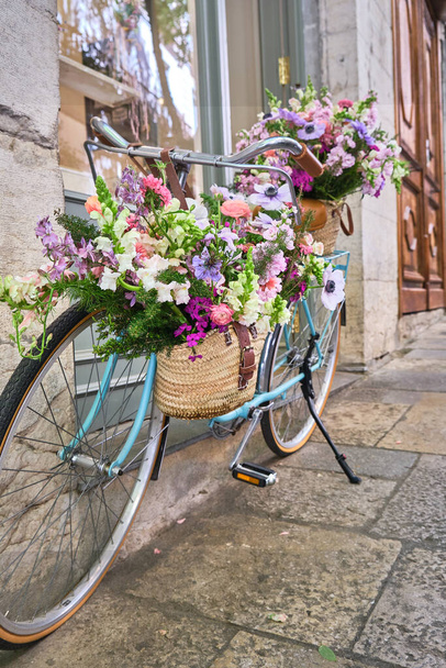 Vintage-Fahrrad mit Weidenkörben am Lenker voller schöner Blumen geschmückt, Girona Blumenfest, temps de flors, Katalonien, Spanien - Foto, Bild