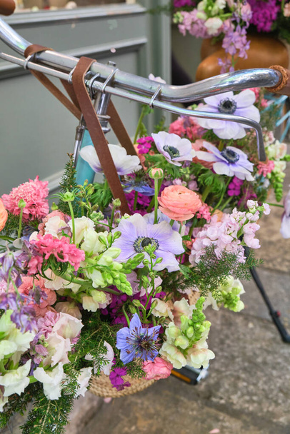 vintage bicycle decorated with wicker baskets hanging from the handlebars full of beautiful flowers, girona flower festival , temps de flors, catalonia, spain - Photo, Image