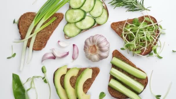 Sandwich with avocado, cucumber, olives and green onions on a wooden board. - Footage, Video