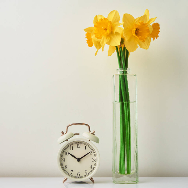 Alarm clock and flowers in vase on white background - Photo, Image