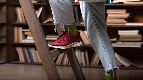 student climbs the stairs on the bookshelf in the library. university library - Foto, imagen