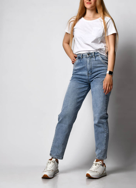 Unknown young skinny woman dressed in stylish blue jeans and white sneakers. - Foto, immagini