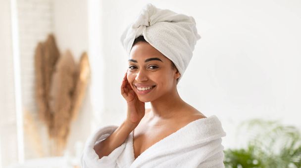Happy Black Lady toucher le visage avec une peau lisse dans la salle de bain - Photo, image