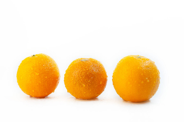 A closeup shot of three oranges covered with water droplets isolated on a white background - Valokuva, kuva