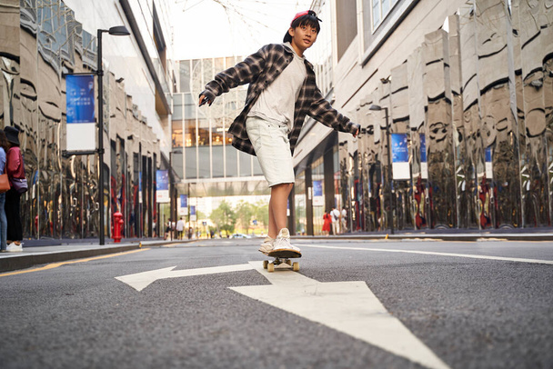 10代のアジア系の子供が屋外でスケートをし - 写真・画像