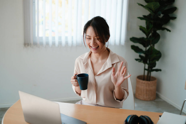 Uma mulher alegre com xícara de café concentra-se em um webinar em seu computador portátil. - Foto, Imagem