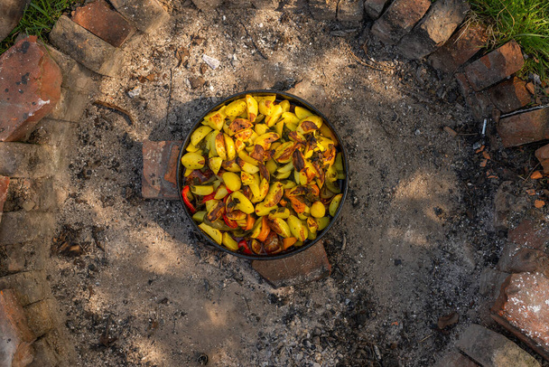 Photo of Cooking traditional dalmatian, croatian, bosnian dish called peka. Meat, potatoes and vegetables in pot and covered with hot charcoal and ash. Balkan food. - Fotoğraf, Görsel
