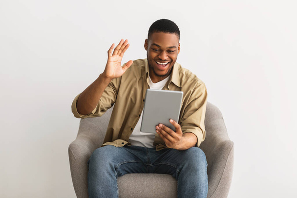 Happy Black Guy Video Calling Via Digitális Tablet, szürke háttér - Fotó, kép