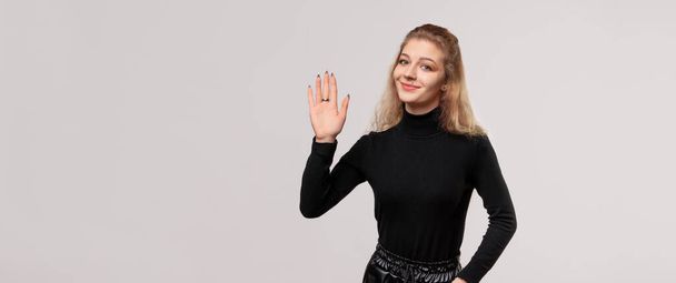 Freundliches blondes Mädchen grüßt, grüßt mit glücklicher Miene, zeigt fünf Finger, freundliche Willkommensgeste - Foto, Bild