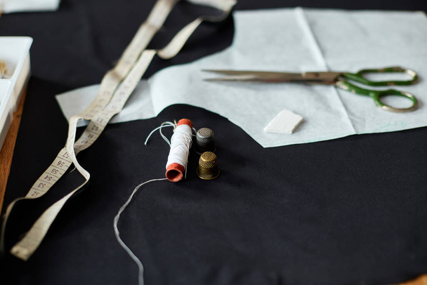 Vista superior de los suministros de costura en una mesa de madera: hilo de coser, tijeras, piezas de tela, agujas, centímetro, patrón. - Foto, imagen