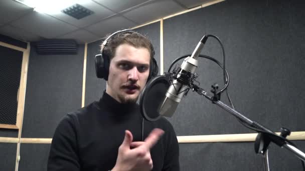 Φωνητικός ηθοποιός με ακουστικά στο στούντιο ηχογράφησης ζητά από το σκηνοθέτη να παίξει το ρόλο του - Πλάνα, βίντεο