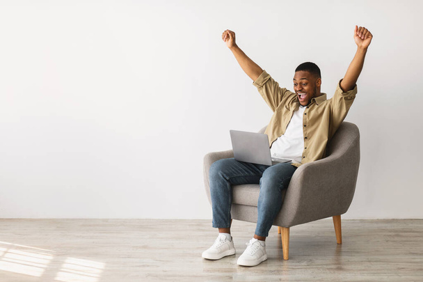 Joyful African Male Using Laptop Shaking Fists Over Gray Wall - Photo, Image