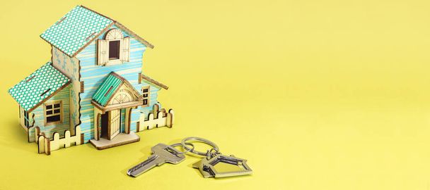 Koncept hypotečního a nájemního bydlení a nemovitostí. Hypoteční úvěry. Dům si hraje s klíči na žlutém pozadí. Formát nápisu - Fotografie, Obrázek