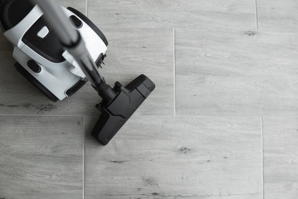 Bagless cyclone vacuum cleaner on a grey tile. Electrical apparatus that by means of suction collects dust and small particles from floors and other surfaces. - Foto, afbeelding