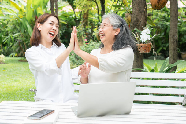Asian daughter teaching old elderly woman use online Social media in computer laptop after retirement. Concept of Learning technology and adaptation of the elderly - Photo, Image