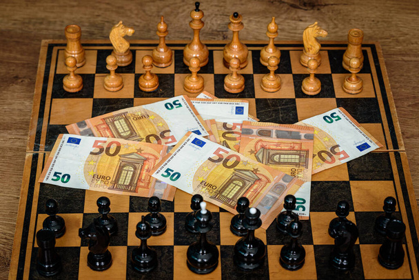 een schaaktafel met cijfers en echt geld dat gespeeld of gewonnen zal worden als een overwinning - Foto, afbeelding