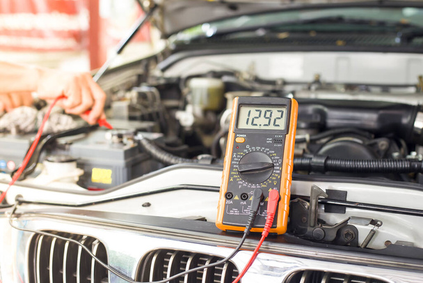 Um técnico está verificando a bateria do carro para a disponibilidade.; - Foto, Imagem