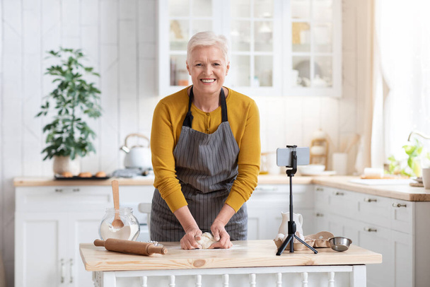 Ελκυστική ηλικιωμένη κυρία μαγείρεμα στο σπίτι, βλέποντας online τάξη - Φωτογραφία, εικόνα