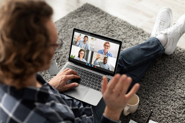 Joven chico usando latop ordenador para hablar con su equipo de negocios, saludando de la mano en la webcam, hablando con sus compañeros de trabajo o amigos - Foto, imagen