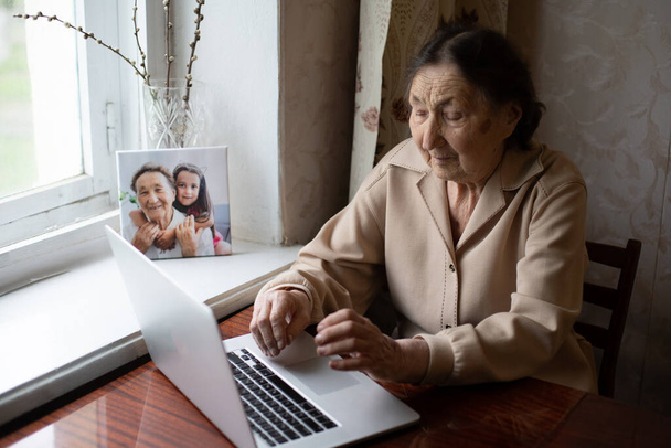 velmi stará žena pomocí notebooku sedí doma - Fotografie, Obrázek