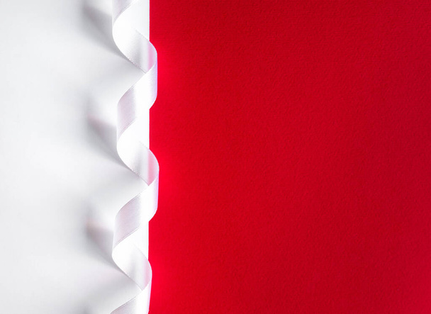 ミニマルなリボンの装飾が施された赤と白の紙の背景。コントラストとミニマリズムの概念。テキスト用のコピースペース付きカード. - 写真・画像