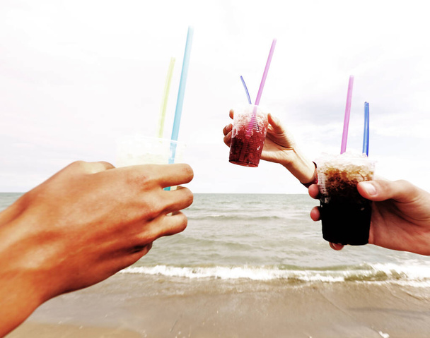 Tre mani che fanno un brindisi con granatina fredda con sciroppo zuccherato in riva al mare in estate con vecchio effetto tonico - Foto, immagini