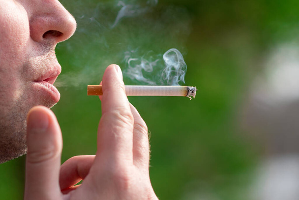 Gesneden close-up man roken sigaret buiten schot. - Foto, afbeelding