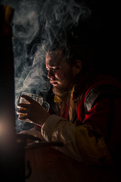 Witcher in a bar with smoke drinking beer - Zdjęcie, obraz