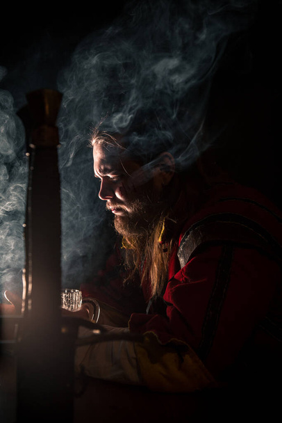 Witcher in a bar with smoke drinking beer - Фото, зображення