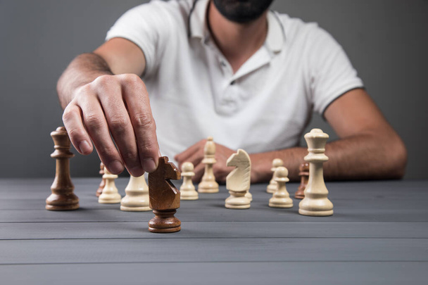 vista di un uomo che tiene un pezzo di scacchi in mano su uno sfondo grigio - Foto, immagini