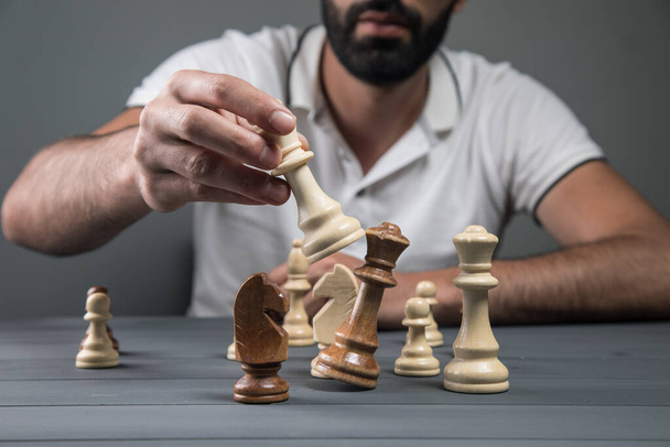άποψη ενός άνδρα κρατώντας ένα πιόνι σκάκι στο χέρι του σε ένα γκρι φόντο - Φωτογραφία, εικόνα