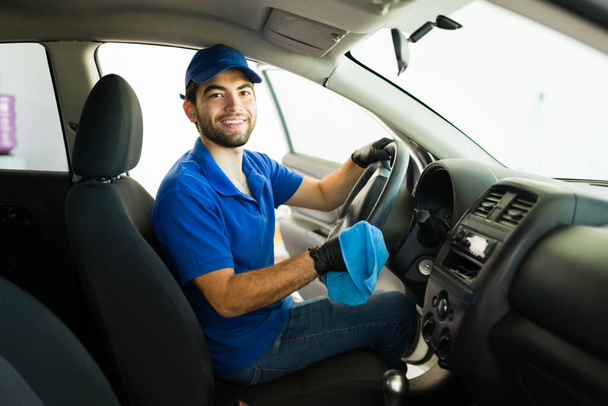 Feeling happy to be doing an excellent job at my job at the car wash. Portrait of a latin young man smiling and making eye contact while sitting inside a customer vehicle - Photo, Image