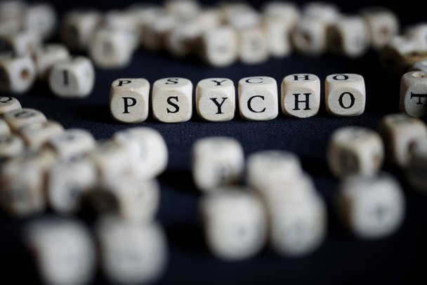Sana psyko koostuu monista kirjainkuutioista pimeällä pinnalla. Psykologia, psykoanalyysi, psykoterapia ja mielenterveyden häiriöt käsite. lähikuva - Valokuva, kuva