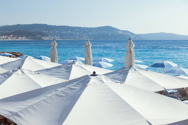Parapluies blancs sur une plage avec des montagnes en arrière-plan - Photo, image