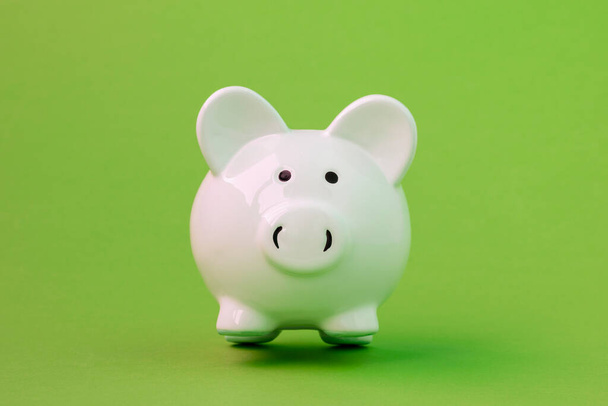 White ceramic piggy bank on green background. Financial savings. - Foto, afbeelding