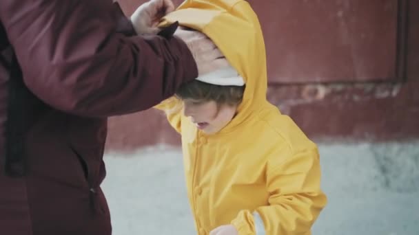 Mom puts hood on girl during strong gusts of wind. Concept of strong wind gusts - Footage, Video