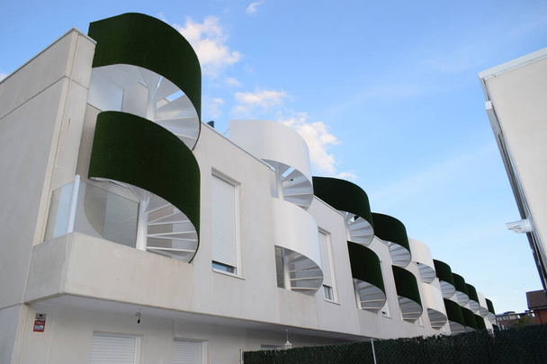 Fachada de casas de nueva construcción en color blanco y con césped artificial verde decorando las escaleras - Foto, imagen