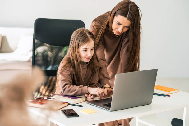 Mother and daughter are doing homework at the laptop - Photo, Image
