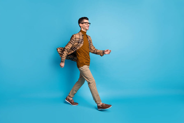 Full size profile side photo of young handsome smiling positive good mood man go walk isolated on blue color background - Φωτογραφία, εικόνα