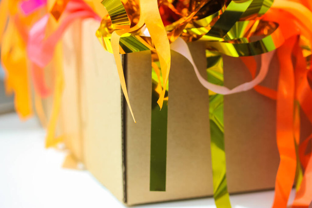 Бумажные гирлянды в картонной коробке крупным планом. Абстрактные красочные праздничные бумажные ленты, блестящая бумага, ленты. Празднование кудрявые смешанные золотые, желтые, розовые ленты. Поздравления, праздничное мероприятие, веселье. - Фото, изображение